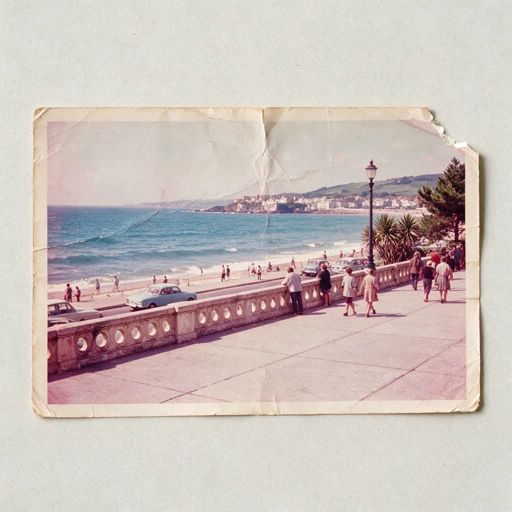 Creased and torn 1960s colour snapshot of a seaside promenade with faded magenta shifted dye and a missing corner